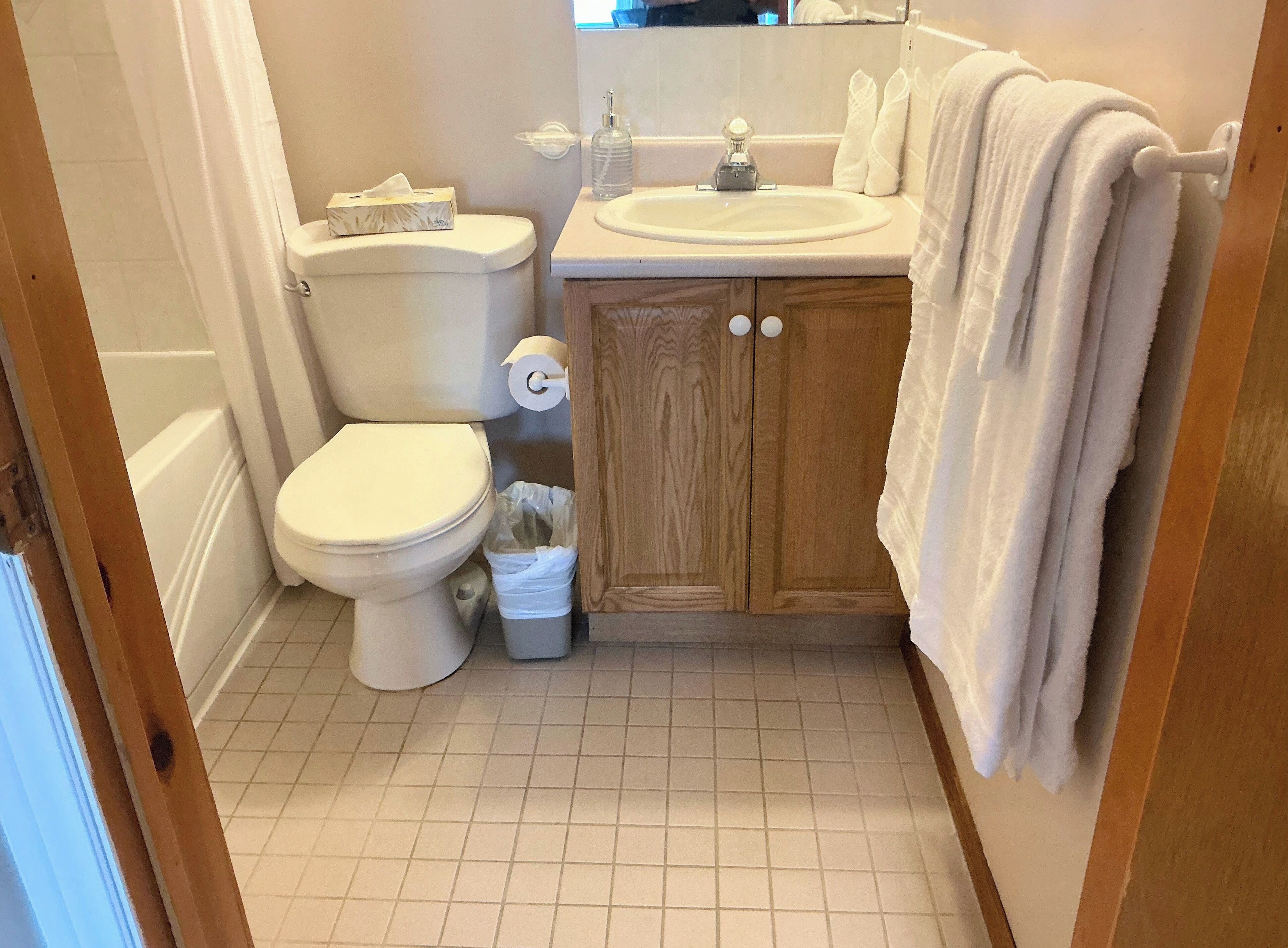 A small bathroom with a toilet, sink, and wooden cabinet.