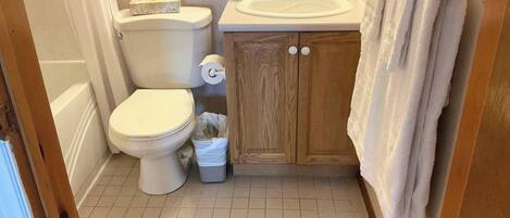 A small bathroom with a toilet, sink, and wooden cabinet.