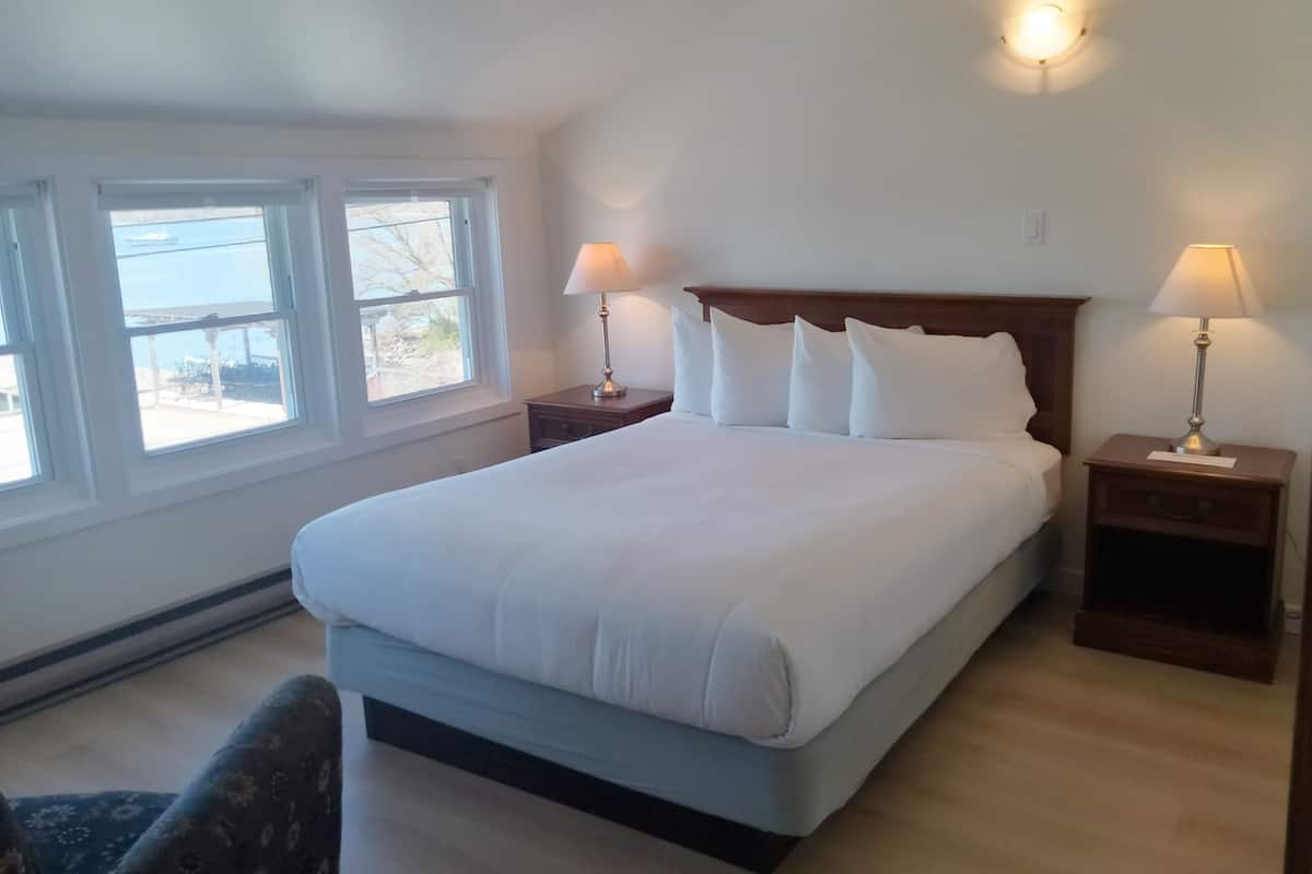 Una camera da letto con un letto grande, due comodini con lampade, una finestra con vista e una trave in legno al soffitto.