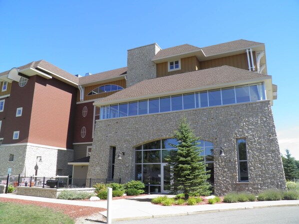 A multi-story building with a stone facade, large windows, and a landscaped front yard.