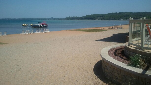 Une plage avec un quai pour bateaux, des chaises longues et une structure en pierre dotée d’une balustrade.