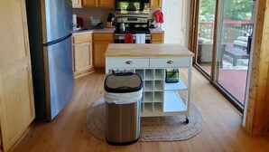 Una cocina compacta con armarios de madera, un refrigerador de acero inoxidable, un microondas y una pequeña mesa de comedor.