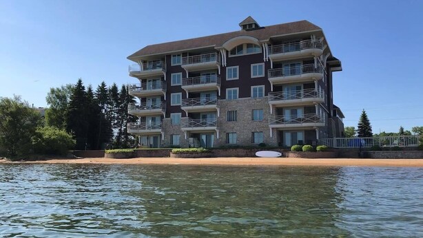A multi-story hotel with balconies, located near a body of water. - Lovely 2-bedroom Suite with lots of Amenities (Traverse City)