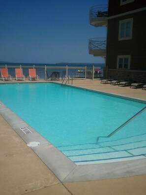 A swimming pool with lounge chairs and a view of the ocean.