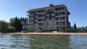 Een hotel met meerdere verdiepingen en balkons, gelegen nabij een waterpartij.