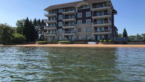 A multi-story hotel with balconies, located near a body of water.