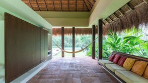 A covered outdoor area with a hammock, a sofa with cushions, and a view of greenery. - Yeguas Y41 by Wynwood House  (Anapoima)