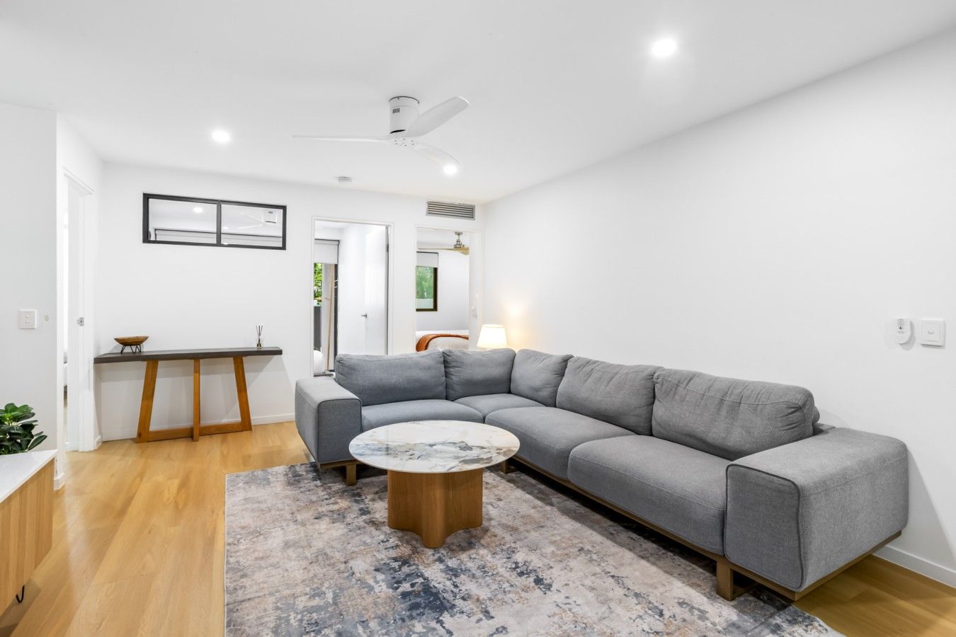 A modern living room with a grey sectional sofa, a round coffee table, and a wooden dining table.