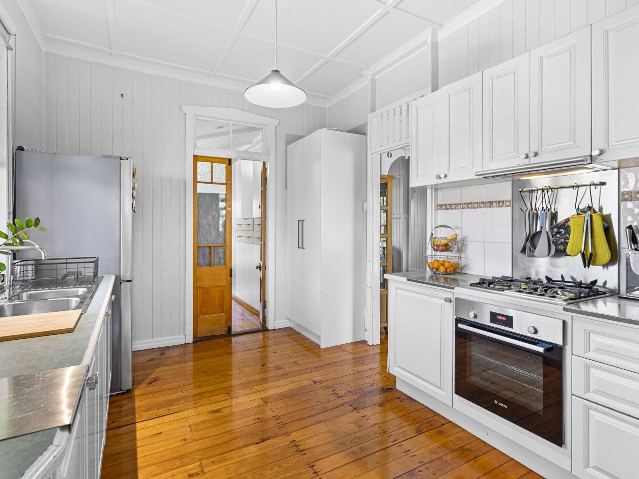 A kitchen with white cabinetry, a stainless steel refrigerator, a gas stove, and an oven.