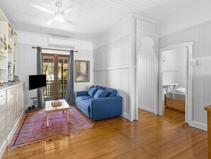 A room with a blue sofa, a wooden table, a TV, and a patterned rug. - Central Location, character home (Grange)