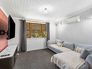 Ein Zimmer mit einem Bett, einem Fernseher, einem Schreibtisch und einem fenster mit Vorhängen.