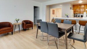 Ein moderner Essbereich mit einem Holztisch, grauen Stühlen und einem braunen Ledersessel.