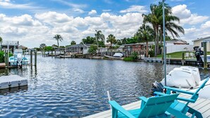 A marina with boats docked, a wooden dock with chairs, and houses in the background. - Heated pool on water, 3-bedroom house in beautiful Tampa (Tampa)