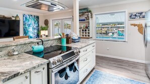 A modern kitchen with a large island, built-in oven, and a window overlooking a pool. - Heated pool on water, 3-bedroom house in beautiful Tampa (Tampa)