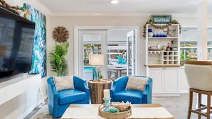 A living room with two blue sofas, a coffee table, and a TV. There is a door leading to a balcony with a pool view. - Heated pool on water, 3-bedroom house in beautiful Tampa (Tampa)