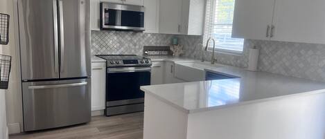 A modern kitchen with stainless steel appliances, white cabinetry, and a large island.