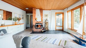 Una sala de estar acogedora con chimenea, techo de madera y ventanas amplias.