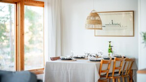 Un comedor con una mesa dispuesta para cuatro personas, una lámpara colgante y un cuadro en la pared.