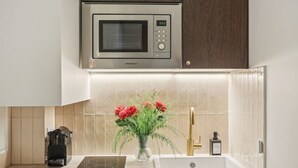 Una cocina equipada con microondas, cafetera y lavabo.