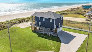 Een huis met twee verdiepingen en een balkon dat uitkijkt op een strand.
