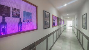 Un couloir aux murs ornés de photographies encadrées, doté d’un sol carrelé et d’une rambarde le long d’un des murs.