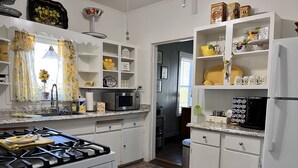 Una cocina con armarios blancos, un microondas, una estufa y un refrigerador.