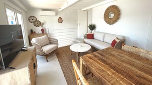 A modern living room with a sofa, a wooden dining table, and a TV. - A little corner of paradise (Toulon)