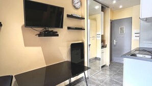 Une cuisine moderne dotée d’un réfrigérateur encastré, d’un plan de travail noir et d’un téléviseur fixé au mur.