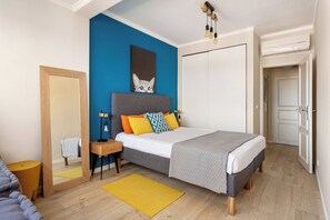 A bedroom with a bed, bedside table, and a mirror. - Stylish flat w/ balcony overlooking the sea (Almada)
