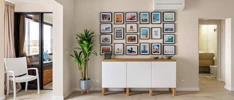 A modern living room with a white cabinet, a potted plant, and a wall decorated with framed pictures.