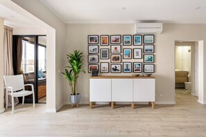 A modern living room with a white cabinet, a potted plant, and a wall decorated with framed pictures.