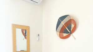 Een kamer met een blauwe houten kast, een gevlochten mand, een ventilator aan de muur en een ingelijste foto.