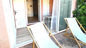 Een balkon met twee ligbedden, een tafel en stoelen.