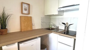 Een compacte keuken met witte kastjes, een houten aanrechtblad, een ingebouwde vaatwasser en een roestvrijstalen spoelbak.