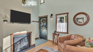 A living room with a fireplace, a television, a sofa, and a window with a view of the outside. - New! Charming private home in historic district. Short walk to downtown Rapid City. Well-appointed and newly renovated. King bed, fireplace, dishwasher, washer/dryer, Wi-Fi, EV charger, tiled shower. Off-street parking. Easy access to I-90. (Rapid City)