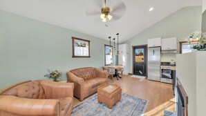 A spacious living room with leather sofas, a dining area, and a kitchen with modern appliances. - New! Charming private home in historic district. Short walk to downtown Rapid City. Well-appointed and newly renovated. King bed, fireplace, dishwasher, washer/dryer, Wi-Fi, EV charger, tiled shower. Off-street parking. Easy access to I-90. (Rapid City)