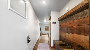 Un pasillo con un banco de madera, un tapete y un cartel en la pared.