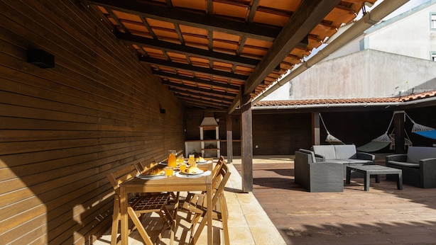 An outdoor patio with a wooden table set for dining, surrounded by wicker furniture.