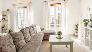 A living room with a patterned sofa, a small table, and a bookshelf.
