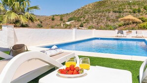 A poolside setting with a table, chairs, a plate of strawberries and orange juice, and a view of a hillside. - Juan Manuel - Los Mangos El Borge by Ruralidays (Málaga)