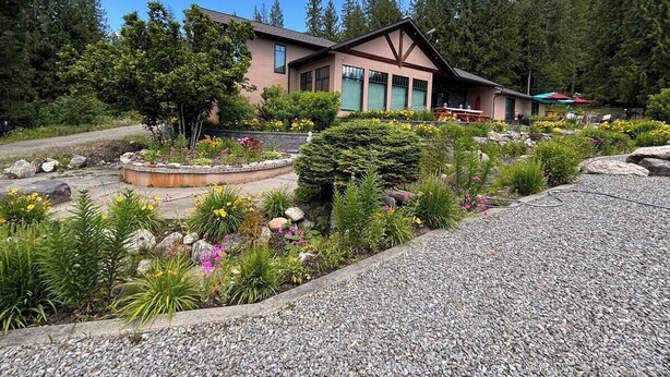 A building with a garden in front, surrounded by trees. - Mara Spring Lodges - Lodge 1 (Mara)
