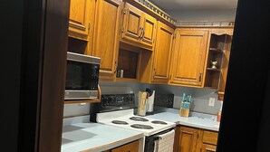 A kitchen with wooden cabinets, a microwave, stove, and a rug. - Cheerful home away from home in welcoming Wausau!  (Wausau)