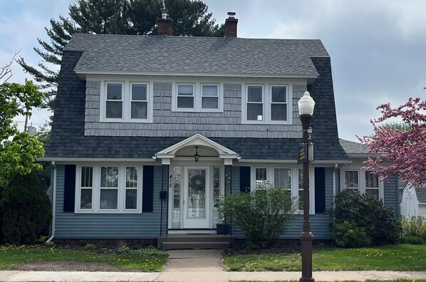 A two-story house with a front porch, a mailbox, and a street lamp.