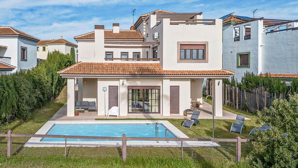 A modern two-story house with a swimming pool, a covered patio, and a fenced garden area.
