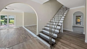 A spacious interior with a central staircase, large windows, and a ceiling fan. - Pool, Beaches, OWA, Dining, and More | Palmaway (Foley)
