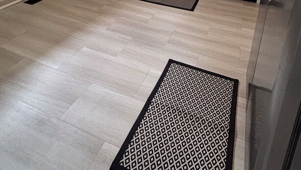 Une cuisine avec un plancher en bois clair, une cuisinière à gaz, des appareils en acier inoxydable et des armoires de couleur claire.