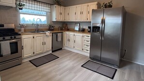 Une cuisine moderne avec des meubles blancs, des appareils en acier inoxydable et une fenêtre offrant une belle vue.