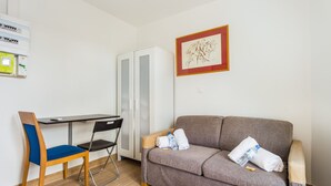 Une pièce comprenant un bureau, une chaise, un canapé et un radiateur.