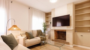 Ein modernes Wohnzimmer mit einer Couch, einem Glastisch und einem Kamin.