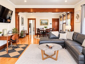 A modern living room with a leather sofa, a round coffee table, and a dining area with wooden furniture.